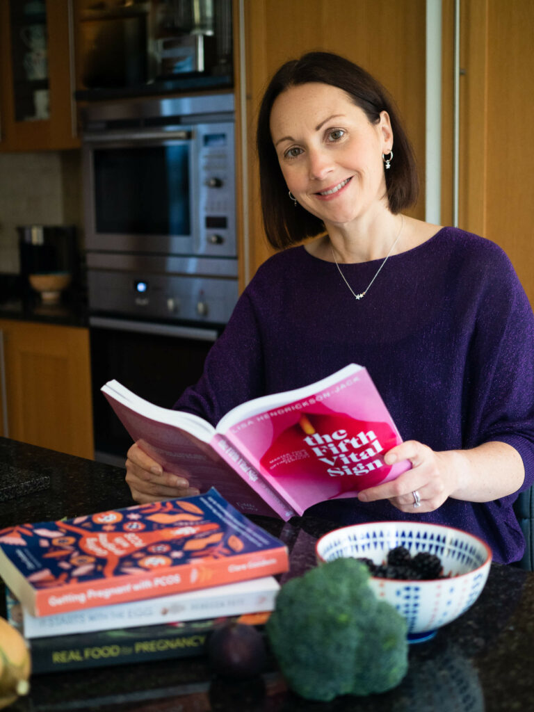 Julia Young holding a fertility book and smiling at the camera